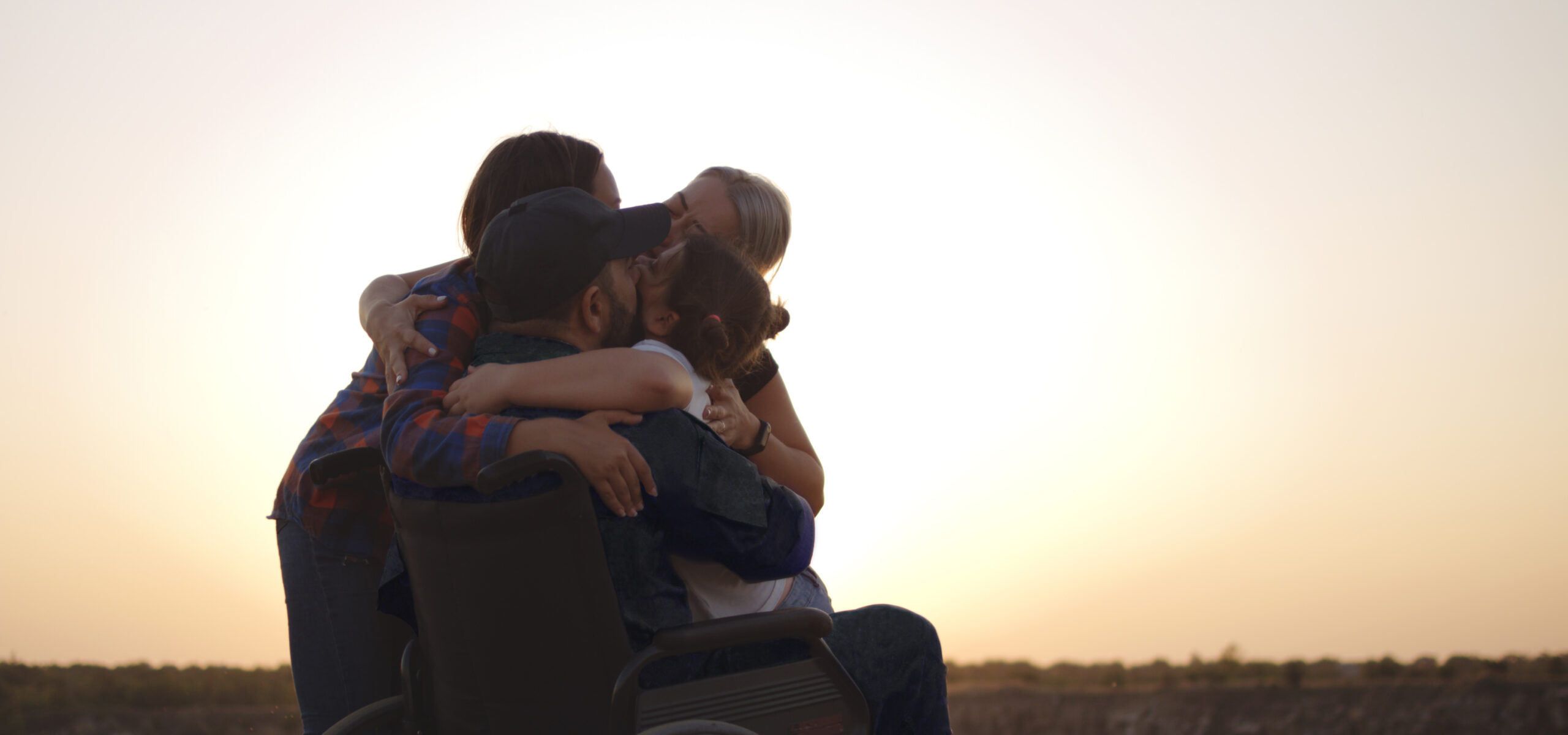 Family hugging father who is in a wheelchair after suffering a work injury