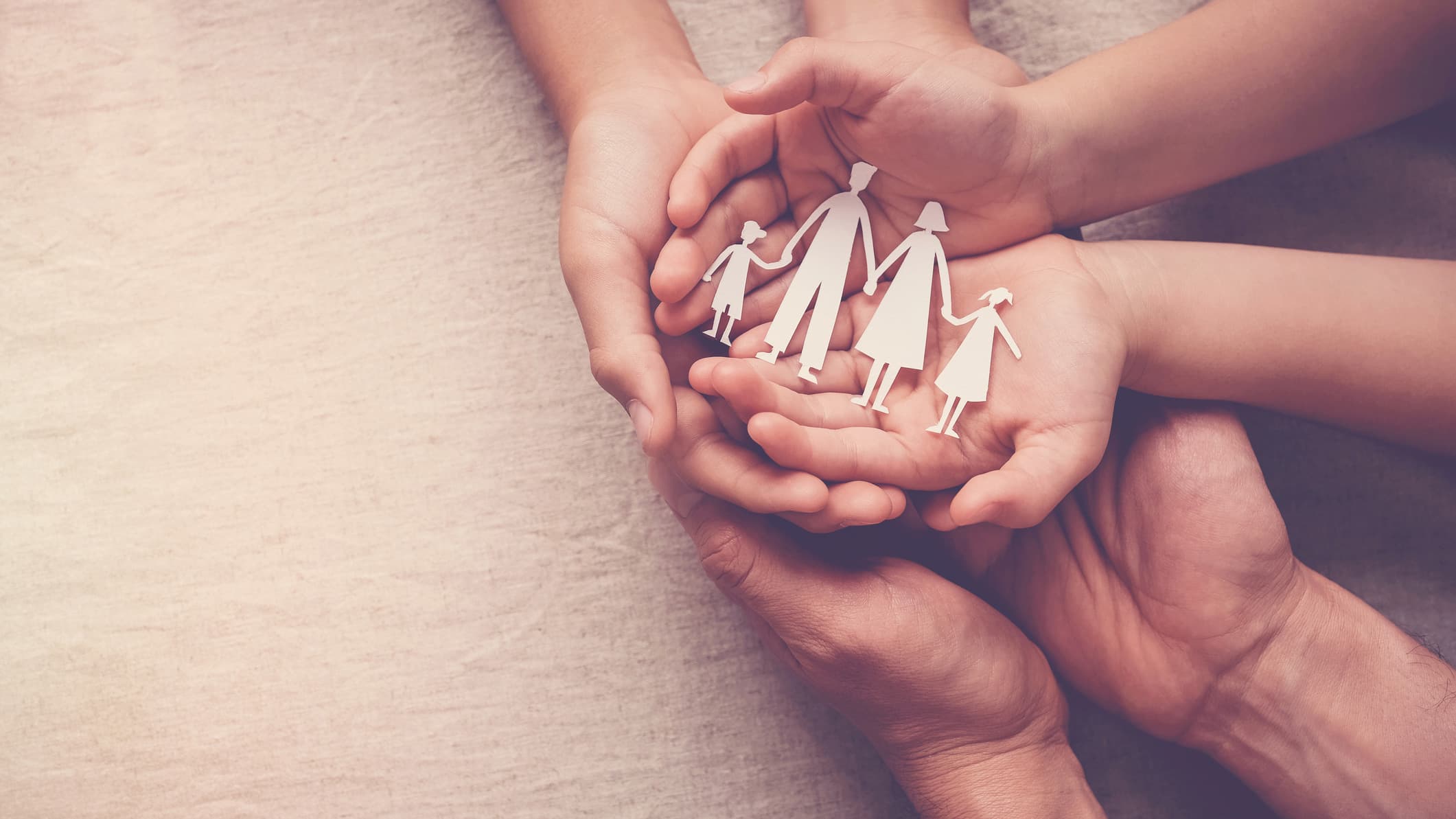 Close up of palms holding a paper cut out of a family