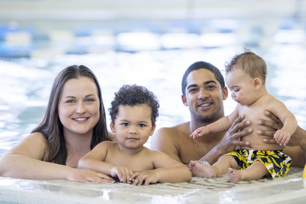 Young family in swimming pool cooling off during the hot heat of summer