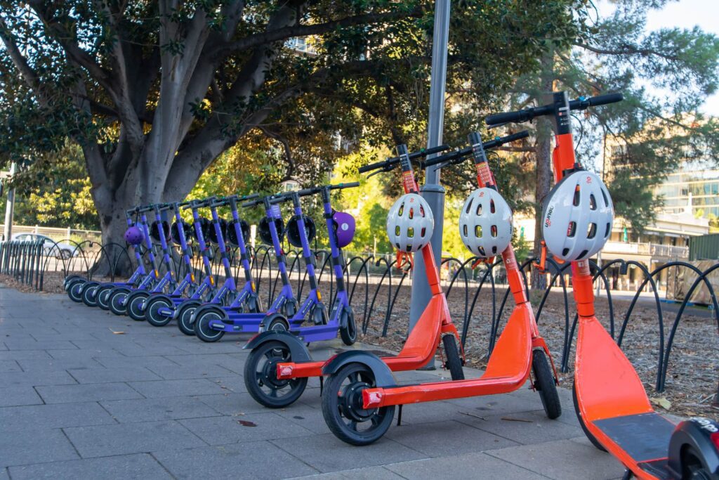 Purple and orange e-scooters lined up on sidewalk