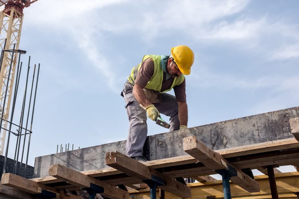 Worker at construction site fixing the form for the beam