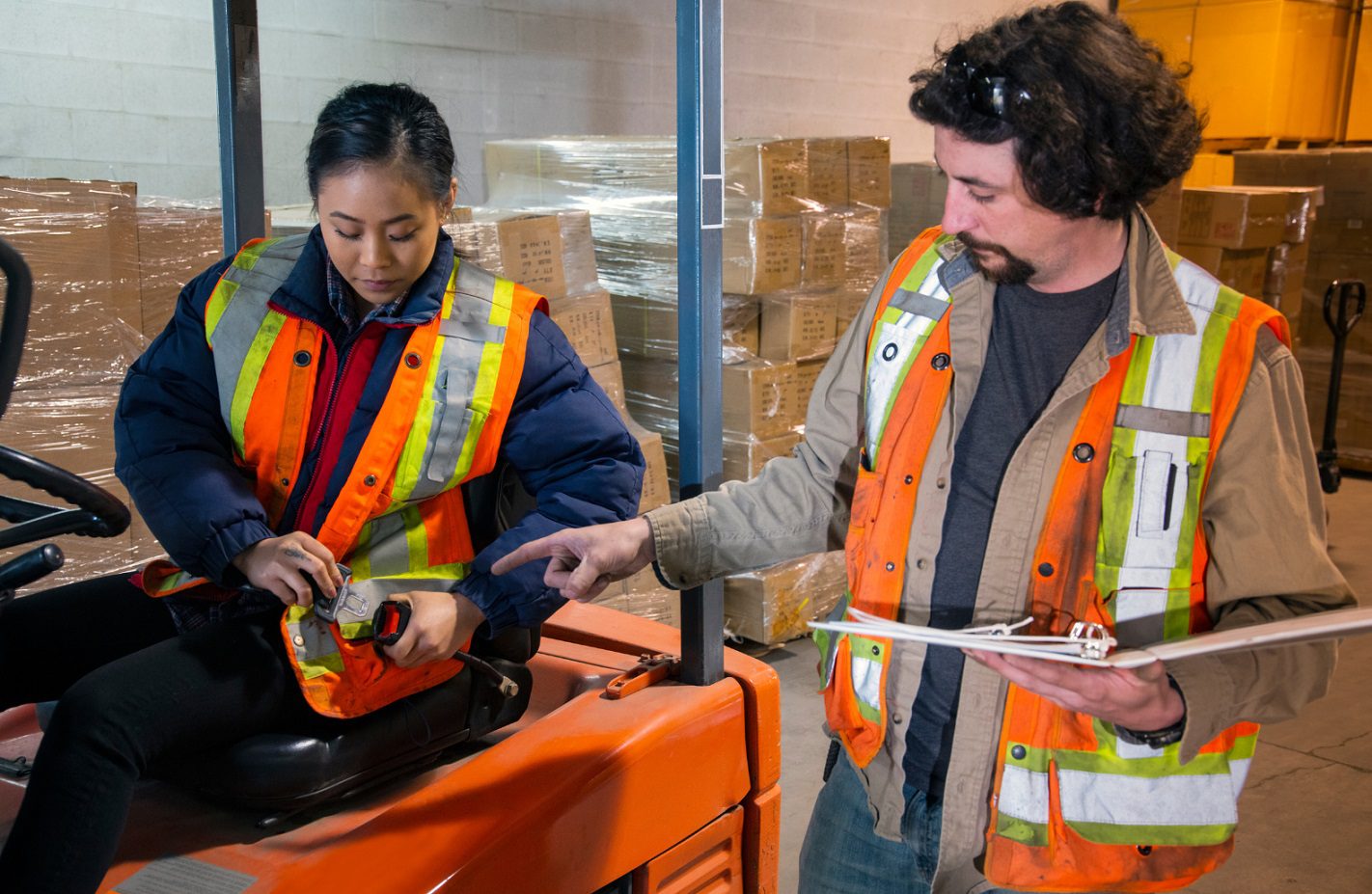 Manager of a warehouse teaching employee importance of workplace health and safety training